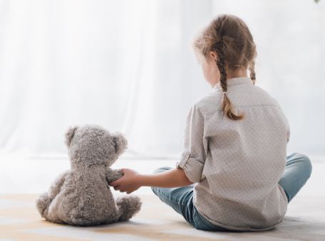 Kind mit Teddy im Kinderzimmer